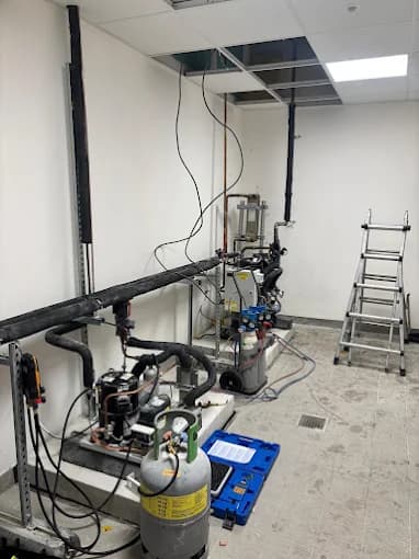 Groupe frigorifique en local technique avec bouteille de fluide frigorigène et manomètres pendant un dépannage