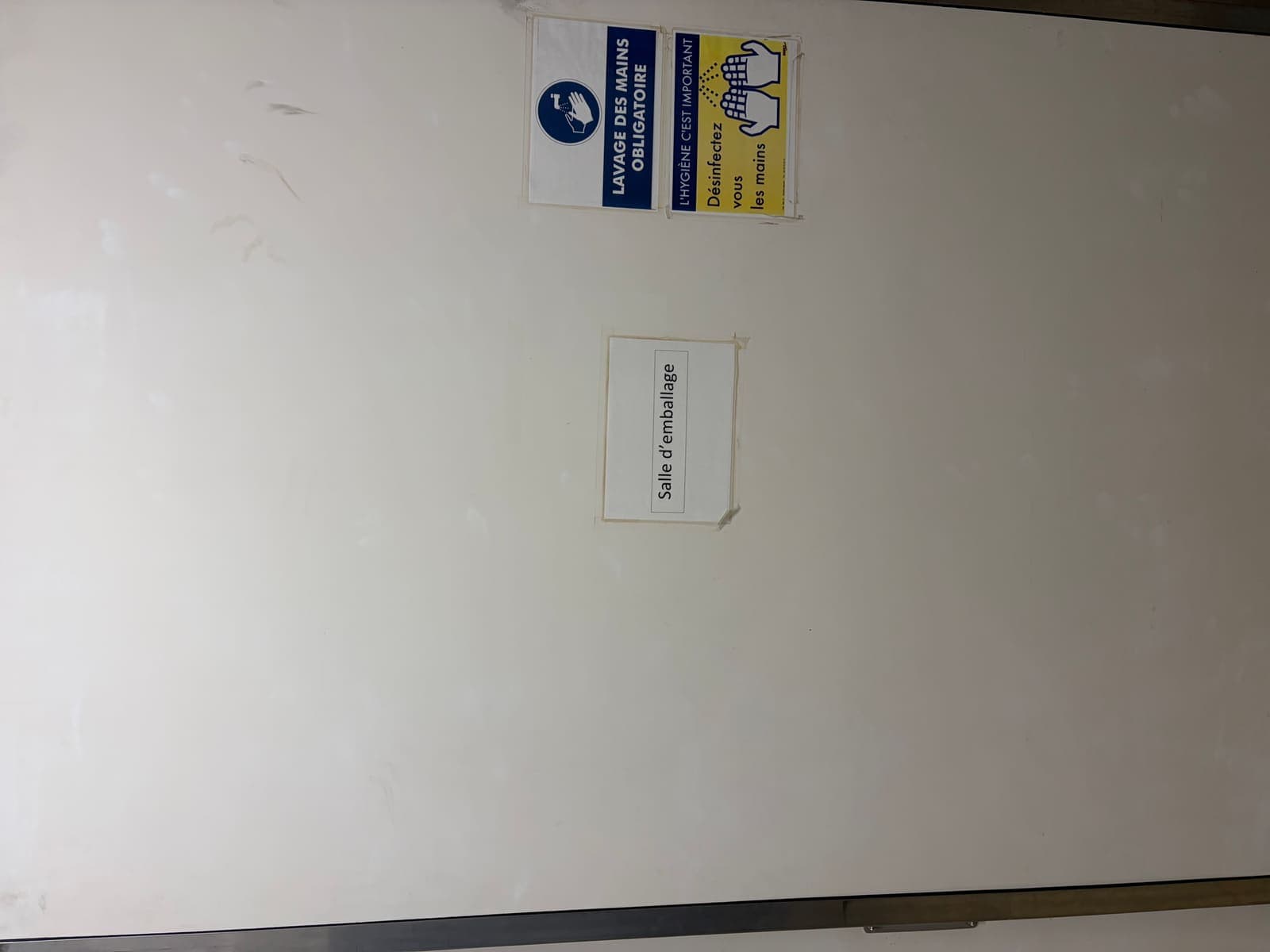 Porte de chambre froide blanche d'une salle d'emballage avec affichage lavage des mains obligatoire, conformité HACCP