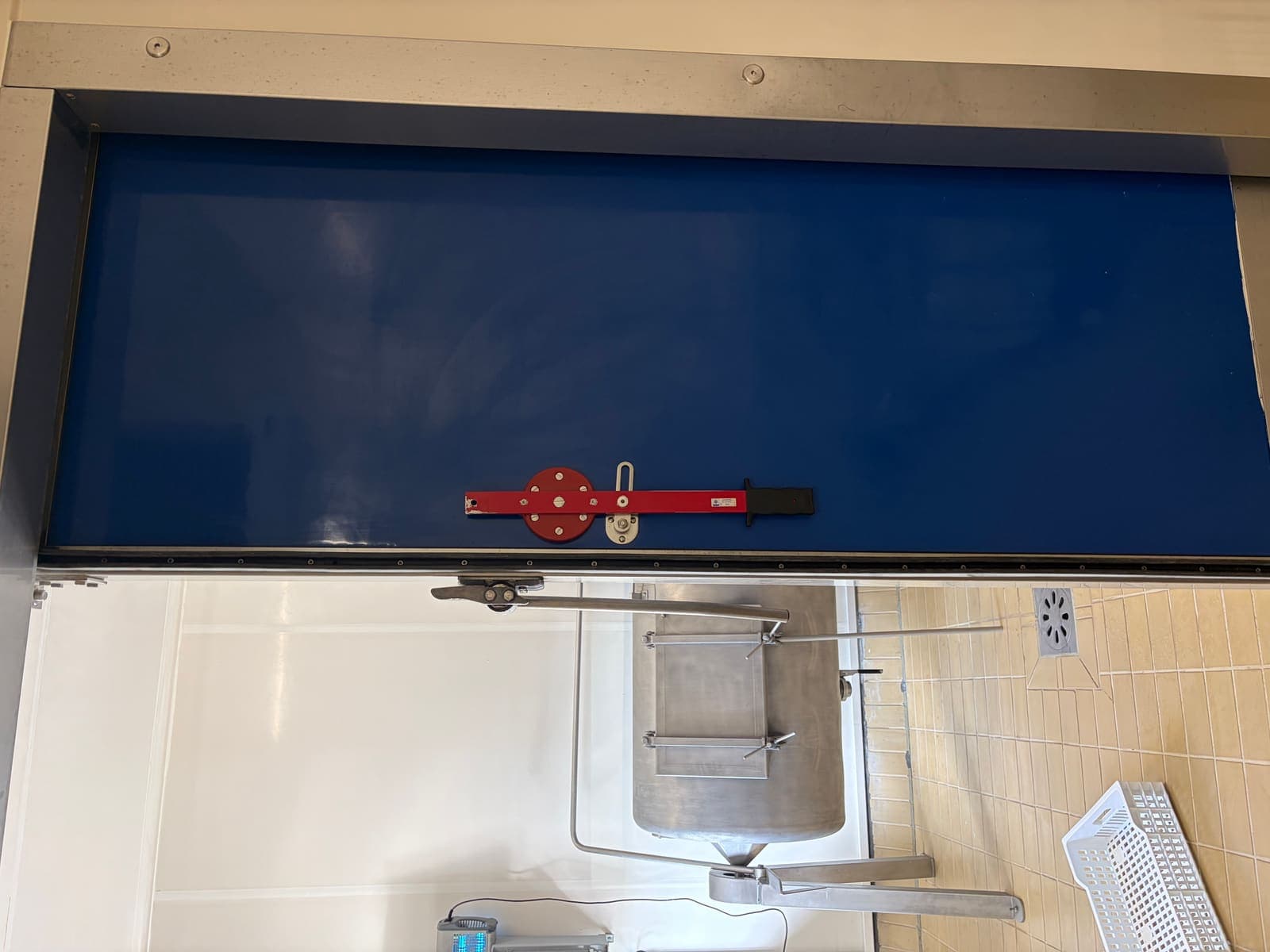Porte de chambre froide bleue fermée avec poignée à came et cadre métallique après remplacement du joint