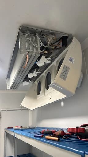 Évaporateur plafonnier en cours de remplacement avec outils sur établi, chambre froide